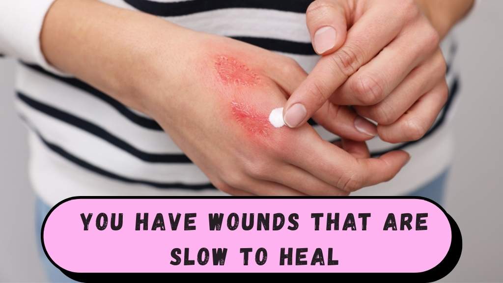 Person examining a small cut or scrape on their hand with a concerned expression, with bandages and antiseptic supplies nearby, showing a slow-healing wound.